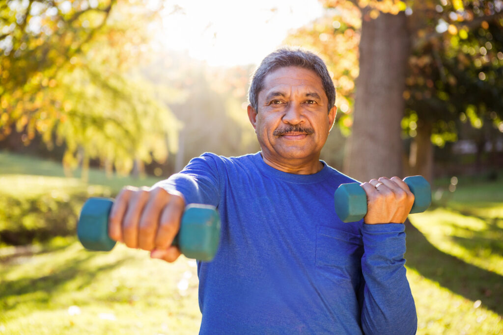 Portrait of mature man exercising with dumbbell at park